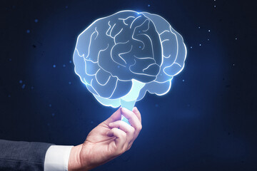Poster - Close up of businessman hand holding glowing human brain hologram on blurry wall background. Neurology research and artificial intelligence concept.