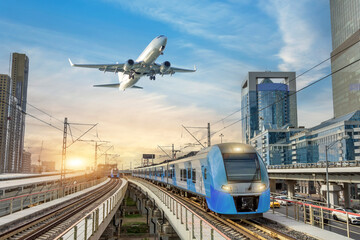 Wall Mural - Urban view of railway tracks and suburban electric trains rushing along among high rise buildings. Passenger plane flying in sky, landing at airport. Concept of modern infrastructure transport travel.