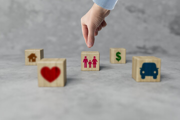 Wall Mural - Wooden blocks with different icons and the hand that chooses the icon with the family. The concept of hierarchy and priorities, the most important family and family happiness.