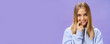 Close-up shot of feminine and tender young girl with fair hair and tanned skin biting finger flirty and shy smiling cute at camera standing in trendy over-sized hoodie, flirting over purple background