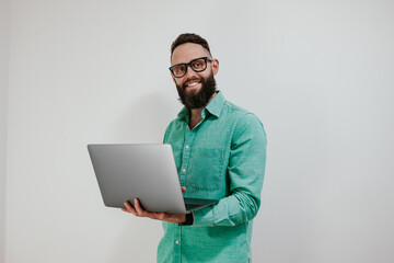 Wall Mural - Portrait of smiling positive businessman standing with portable computer in hands. Laptop concept. Promotion poster. Programmer, web developer holding a laptop in his hands and looking at the camera