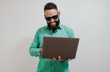 Wall Mural - Portrait of smiling positive businessman standing with portable computer in hands. Laptop concept. Promotion poster. Programmer, web developer holding a laptop in his hands and looking at the camera