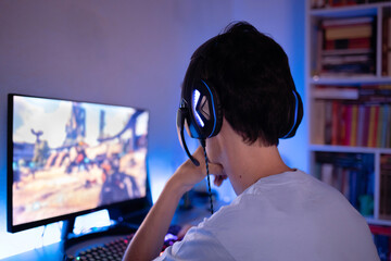 Young man playing online  games on his computer.  Voice chatting through headset