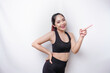 © Reezky - Excited Asian sporty woman wearing sportwear pointing at the copy space beside her, isolated by white background