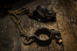 Ancient iron handcuffs on wooden floor from medieval times in England, prisoner wrist restraints.