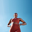 © C Malambo/peopleimages.com - Low angle, sports fitness and black woman outdoor getting ready for workout, training or exercise with mock up. Blue sky, health and female runner thinking of exercising, cardio or jog for wellness.