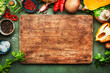 Food background. Rustic wooden cutting board. Vegetables, mushrooms, roots, spices - ingredients for vegan, cooking. Healthy eating, diet, comfort slow food. concept. Old kitchen table, top view