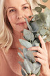 Mature woman, face or skincare plants on studio background in natural dermatology, Canada organic healthcare or vegan wellness. Portrait zoom, smile or middle aged beauty model with eucalyptus leaf