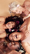 © David L/peopleimages.com - Top view, diversity and women with flowers, cosmetics and skincare on a brown studio background. Multiracial, females and ladies with body positivity, natural beauty or makeup for confidence or smile
