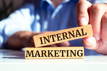 Closeup on businessman holding a wooden blocks with text INTERNAL MARKETING, business concept