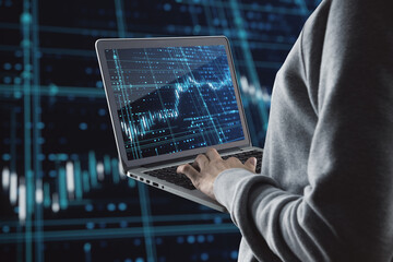 Aufkleber - Close up of hand holding and using laptop computer with glowing forex index chart/graph on dark background. Trade, finance and market concept.