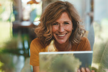 Happy Mature Woman With Tablet PC Seen Through Glass Window