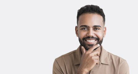 Closeup portrait of handsome smiling young man. Laughing joyful man looking at camera. Studio shot isolated on gray background