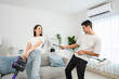 Caucasian young man and woman cleaning living room together at home.