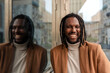 © Renata Hamuda - a handsome laughing african american man leaning against the glass wall looking at the camera