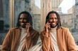 © Renata Hamuda - a smiling handsome african american man leaning against the glass wall talking on the cell phone