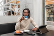 © Renata Hamuda - a modern man with dreadlocks drinking coffee in the cafeteria while using the digital tablet