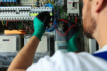 Canvas Print - Electrician checking electric current with multimeter indoors, closeup