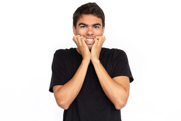 Nervous young man biting nails. Portrait of scared Caucasian male model with short dark hair in black T-shirt looking at camera, nervous about future. Anxiety, fear concept