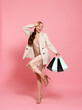 © New Africa - Stylish young woman with shopping bags on pink background