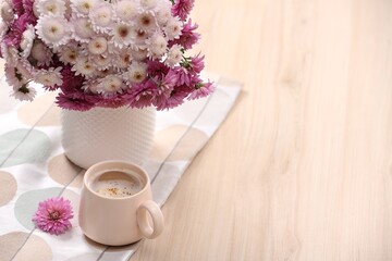 Canvas Print - Cup of hot coffee and beautiful bouquet on wooden table. Space for text