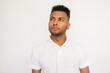 © KAMPUS - Portrait of pensive young man looking away. Male Indian model with brown eyes and curly hair in white polo shirt dreaming or making important decision. Thought, dream concept
