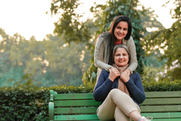 Two indian woman sitting at park in winter wear