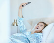 © J Maas/peopleimages.com - Selfie, girl in bed and photography with phone, technology and memory, smile and happy, young gen z with social media content creation. Happiness in picture, morning and smartphone, wifi 5g network.
