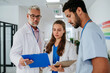 © Halfpoint - Team of doctors discussing something at hospital corridor.