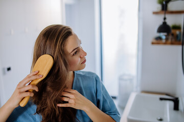 Wall Mural - Young woman taking care of her hair, morning beauty routine concept.