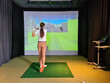 Professional female golfer holding club playing golf indoors on golf simulator.