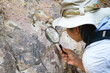 © Pornpimon - Female geologist using a magnifying glass examines nature, analyzing rocks or pebbles. Researchers collect samples of biological materials. Environmental and ecology research.