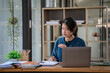 © Songsak C - A beautiful Asian businesswoman analyzes charts using a laptop calculator at the office.