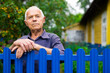 © caftor - Portrait of pensive elderly man at fence of his country house in village
