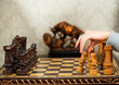 lady making first move with white wooden pawn in chess game at vintage living room interior