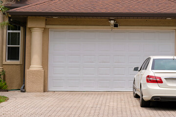 Wall Mural - Vehicle parked in front of wide garage double door on paved driveway of typical contemporary american home