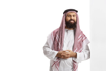 Canvas Print - Saudi arab man wearing a traditional thobe and leaning on a wall