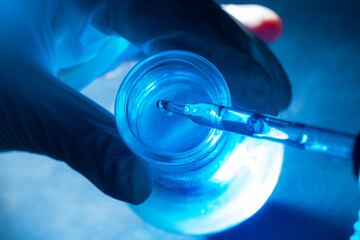 blue science test tube,flask in scientist hand with drop of chemical liquid in test tube science and