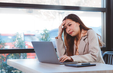 Portrait of a woman using a laptop while sitting at a desk. Asian businesswoman sitting in the office or in a coffee shop