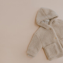 Wall Mural - Warm winter children's jacket. Baby wear on neutral beige background. Fashion Scandinavian children's clothes. Flat lay, top view.