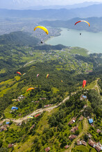 Aerial View Of A Group Of Paragliders Flying Above Sarangkot, Playing In The Thermals, With The City Of Pokhara And Phewa Lake In The Distance, On A Cloudy, Autumn Day; Pokhara, Nepal