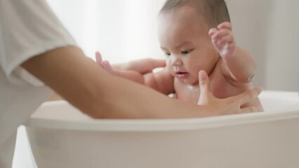 Wall Mural - Closeup view of young Asian mother is Bathing with her newborn baby In Bathtub at home.Concept of newborn,baby,parenthood,motherhood,childhood,New life,maternity,love,new family member