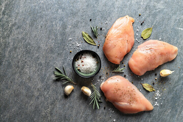Poster - Raw chicken breast with spices on a dark background with copy space top view