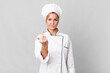caucasian blonde woman feeling angry, annoyed, rebellious and aggressive. chef concept