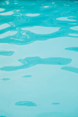 Background, blue water waves in the pool with sun reflection. Top view, selective focus