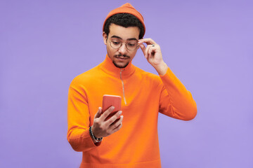 Aufkleber - Young man expressing misunderstanding while touching eyeglasses and looking at smartphone screen with advert or sale announcement