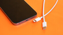USB type C port cable for charging to the smartphone on orange background. EU law to force USB-C chargers. 