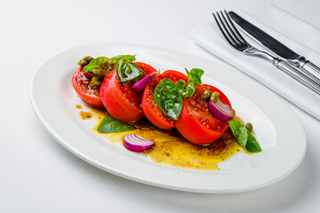 Wall Mural - Tomato salad with red onion and basil on white plate