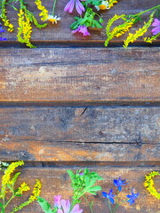 Wall Mural - Multicolored wildflowers are arranged in a circle on a wooden table background. Chamomile, sweet clover, wild geranium, bluebells, parsley inflorescences. Horizontal boards. Romantic Provence style