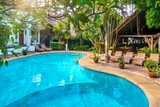 Fototapeta  - Beautiful tropical resort swimming pool with vibrant turquoise water, surrounded by lush, tropical vegetation and resort buildings.
